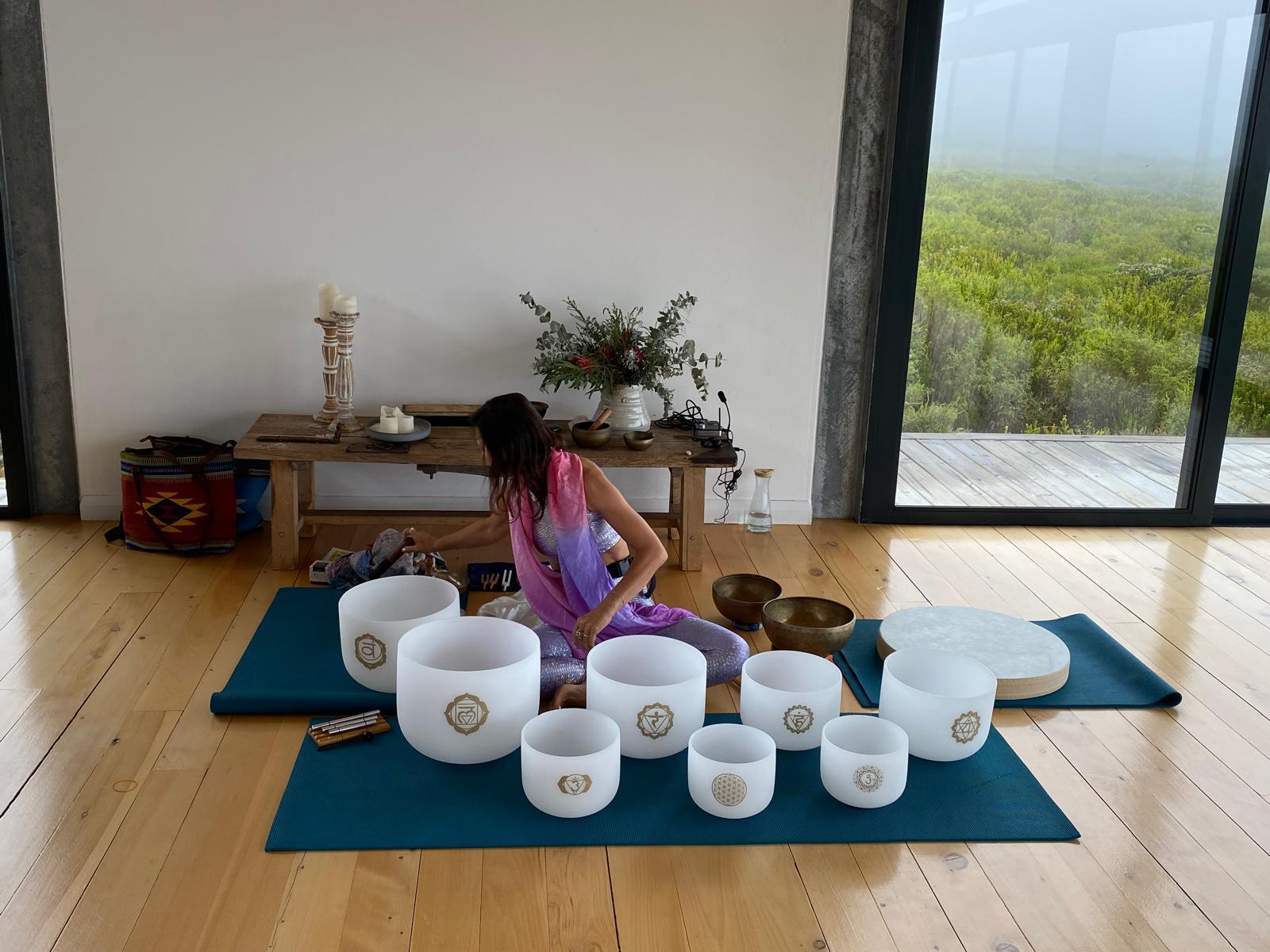 Seven-bowl crystal sound bowl set with Tibetan bowls and an ocean drum, set up for a sound bath